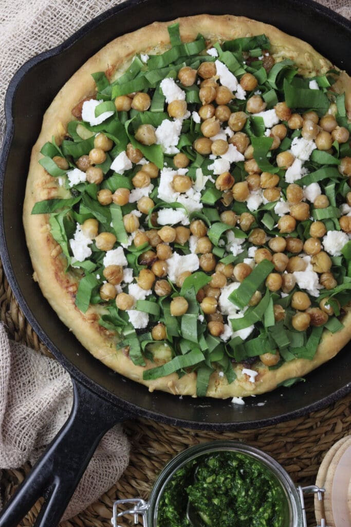 image of wild garlic pizza topped with wild garlic leaves, chickpeas and white feta cheese